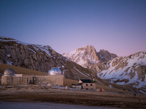 Snowy mountain landscape featuring the Gran Sasso observatory during twilight in Abruzzo, Italy.