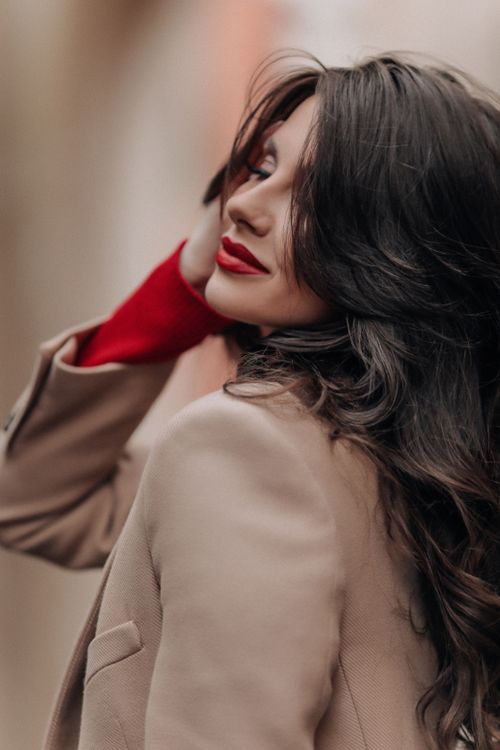 Free Stylish brunette woman posing elegantly in a beige coat, showcasing long hair and a modern fashion style. Stock Photo