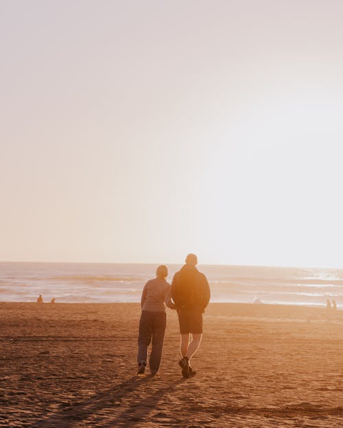 Back View of a Couple Walking on the Beach at Sunset 