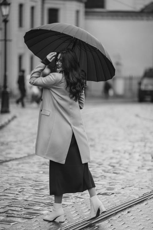 Back View of Woman in Coat on Cobblestone Street in Old Town