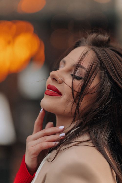 Free Close-up portrait of a brunette woman with elegant red lipstick, hand under chin. Stock Photo