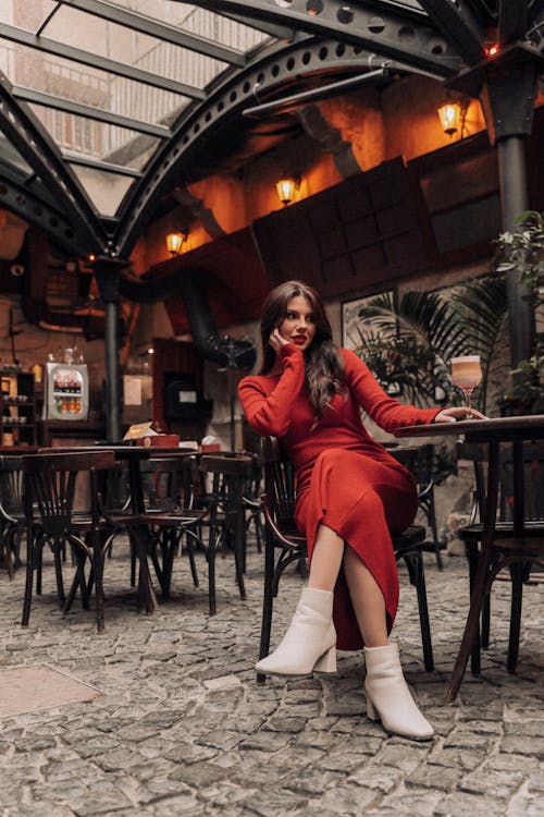 Young Woman in a Red Dress Sitting at a Restaurant Table 