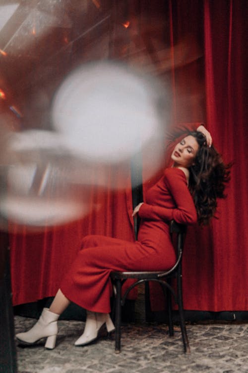 Young Woman in a Red Dress Sitting on a Chair and Fixing her Hair 