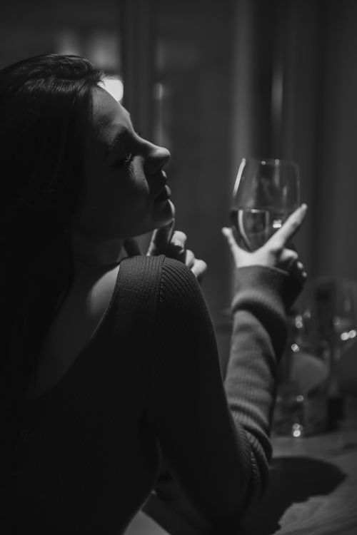 Free Sophisticated black and white portrait of a woman enjoying a glass of wine indoors. Stock Photo