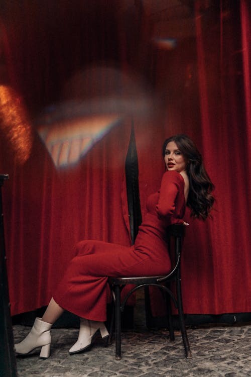 Young Woman in a Red Dress Sitting on a Chair and Posing 