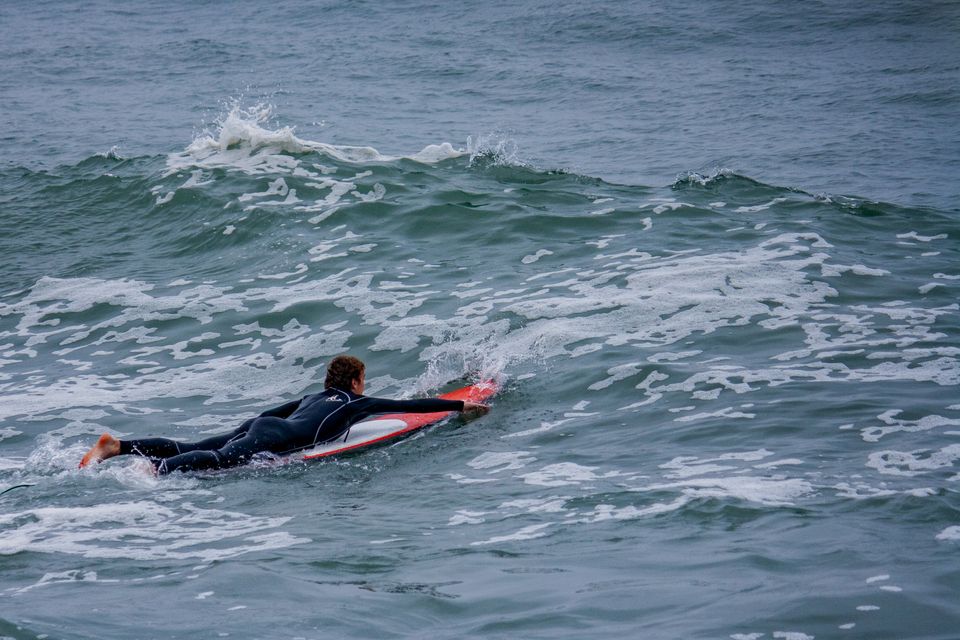 Surfer paddling out through a channel beside the breaking zone