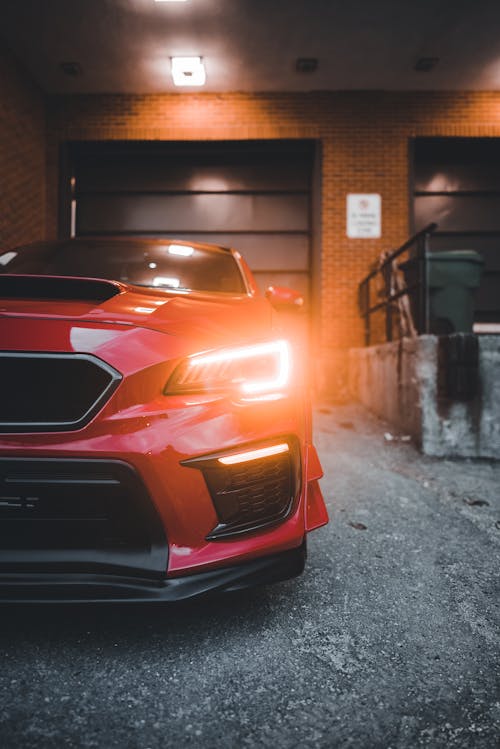 A Red Subaru WRX with Headlights on 