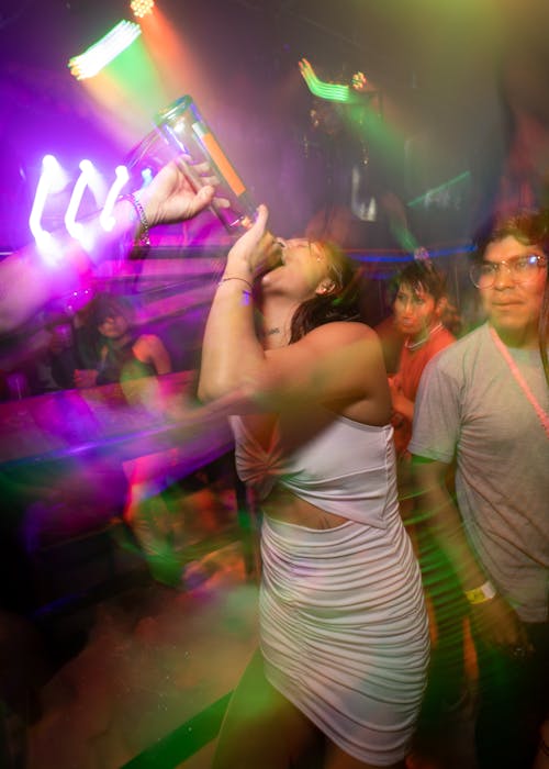 Woman at a Party Drinking Alcohol from a Bottle 