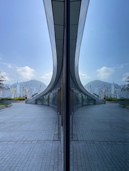 A contemporary building facade reflecting mountains and a blue sky.
