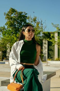 Stylish woman in green attire with sunglasses in Mérida park.