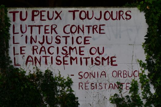 Graffiti on wall with a powerful message against injustice and racism in French.