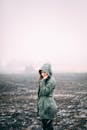 一位年轻女子身穿连帽外套，独自站在雾蒙蒙的雪原上，营造出大气的冬季景象
