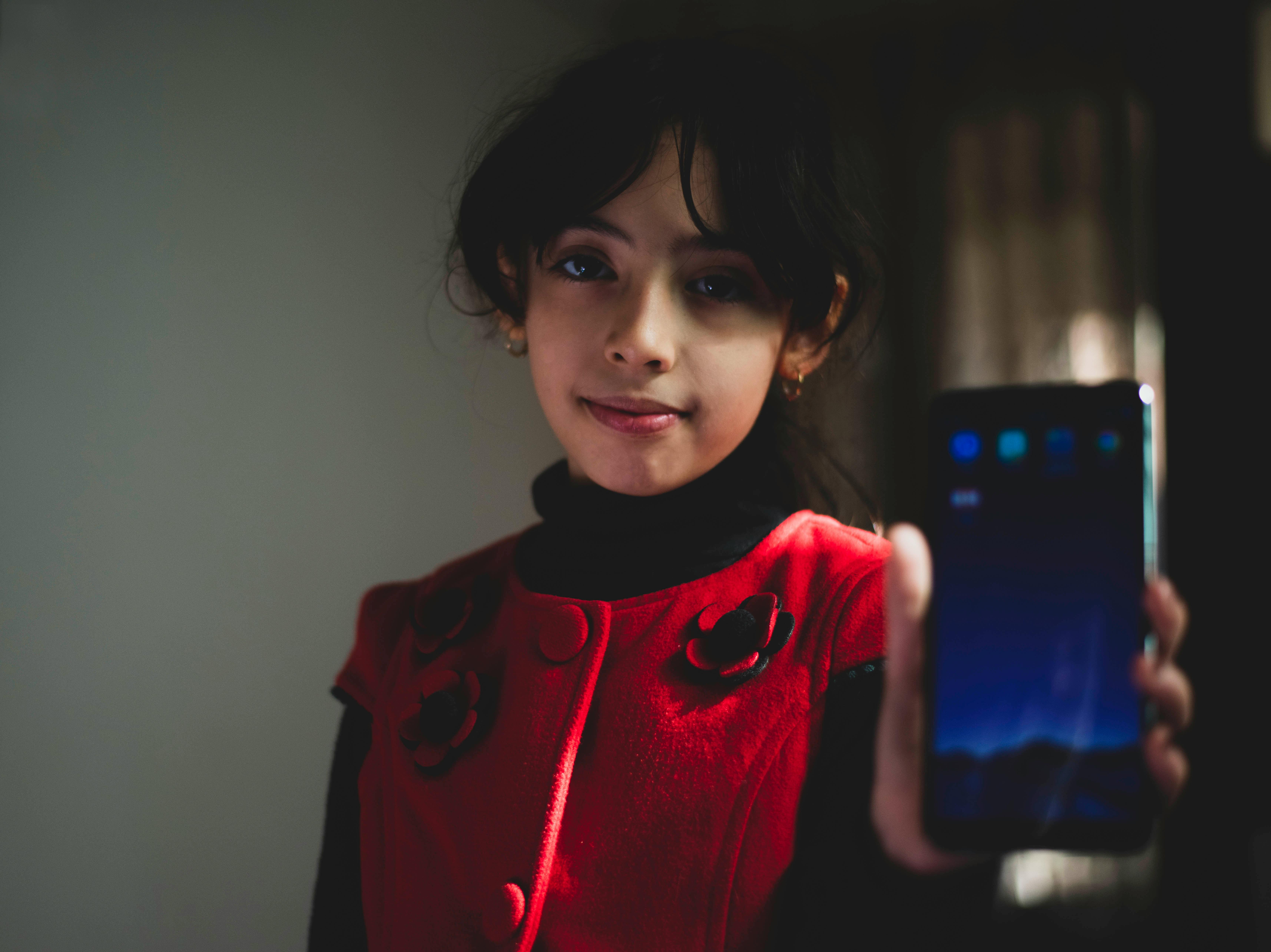 girl wearing red and black top holding smartphone