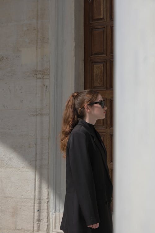 Elegant Woman with Sunglasses Standing by Wooden Door