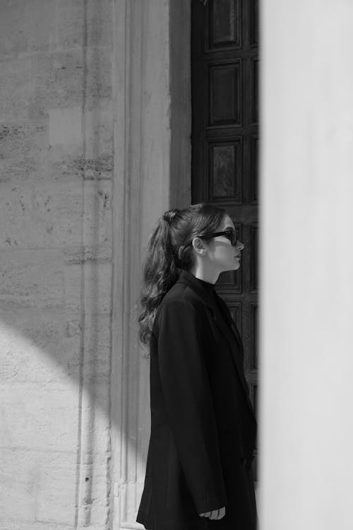 Woman in Black Clothes and Sunglasses Standing near Wall