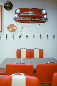 Classic 50s diner theme with red chairs and retro car front wall decor.