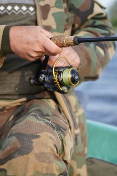 Close-up of a man fishing with rod in camouflage outfit, Jelgava, Latvia.