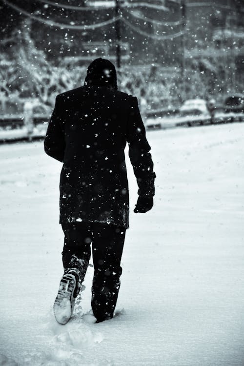 Man in Warm Clothing Walking in Snow