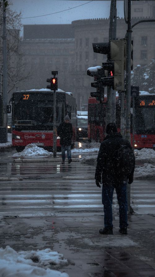 Free Pedestrians and buses navigate a snow-covered street in Belgrade during winter. Stock Photo