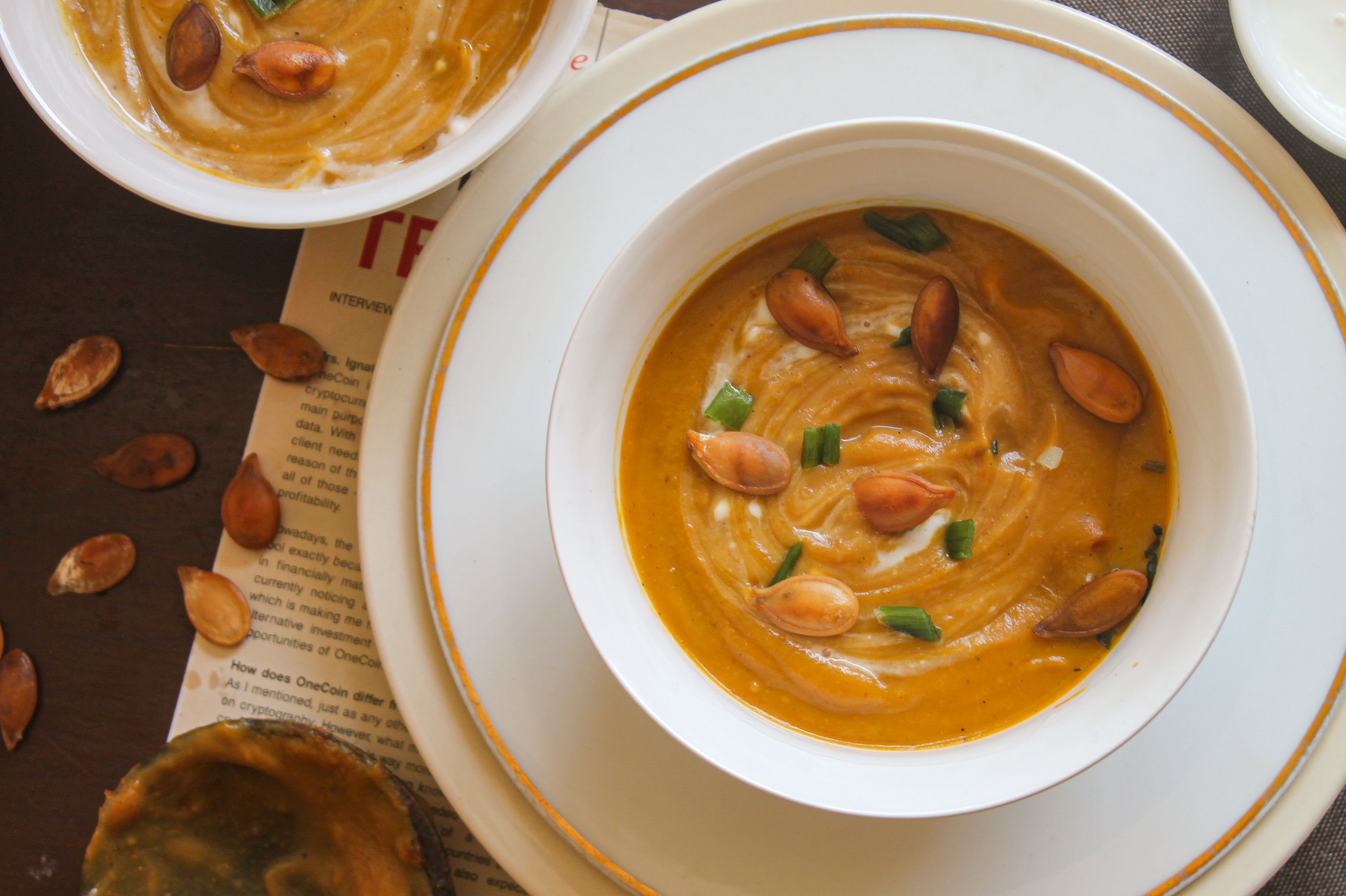 Savor this warm pumpkin soup topped with roasted seeds and green onions, perfect for fall.