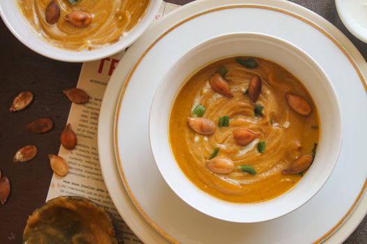 Savor this warm pumpkin soup topped with roasted seeds and green onions, perfect for fall.