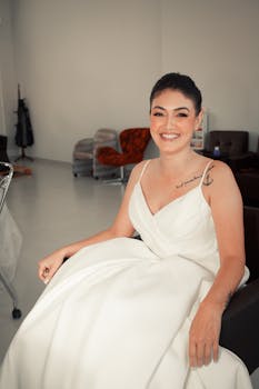 Smiling bride in a wedding dress, showcasing tattoos in a modern salon.