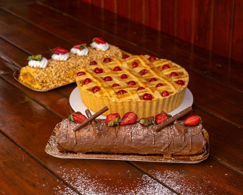 Free A tempting display of pastries including chocolate roulade, fruit tart, and nut cake on a wooden table. Stock Photo