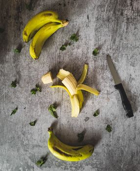 Top view of fresh bananas and knife on a textured gray background, perfect for food concepts.