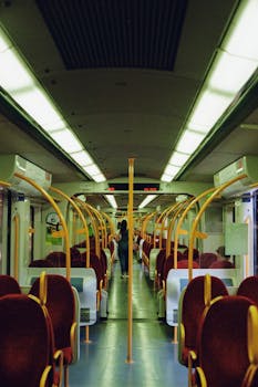 View inside a modern and empty railway carriage featuring red seating and a traveler.