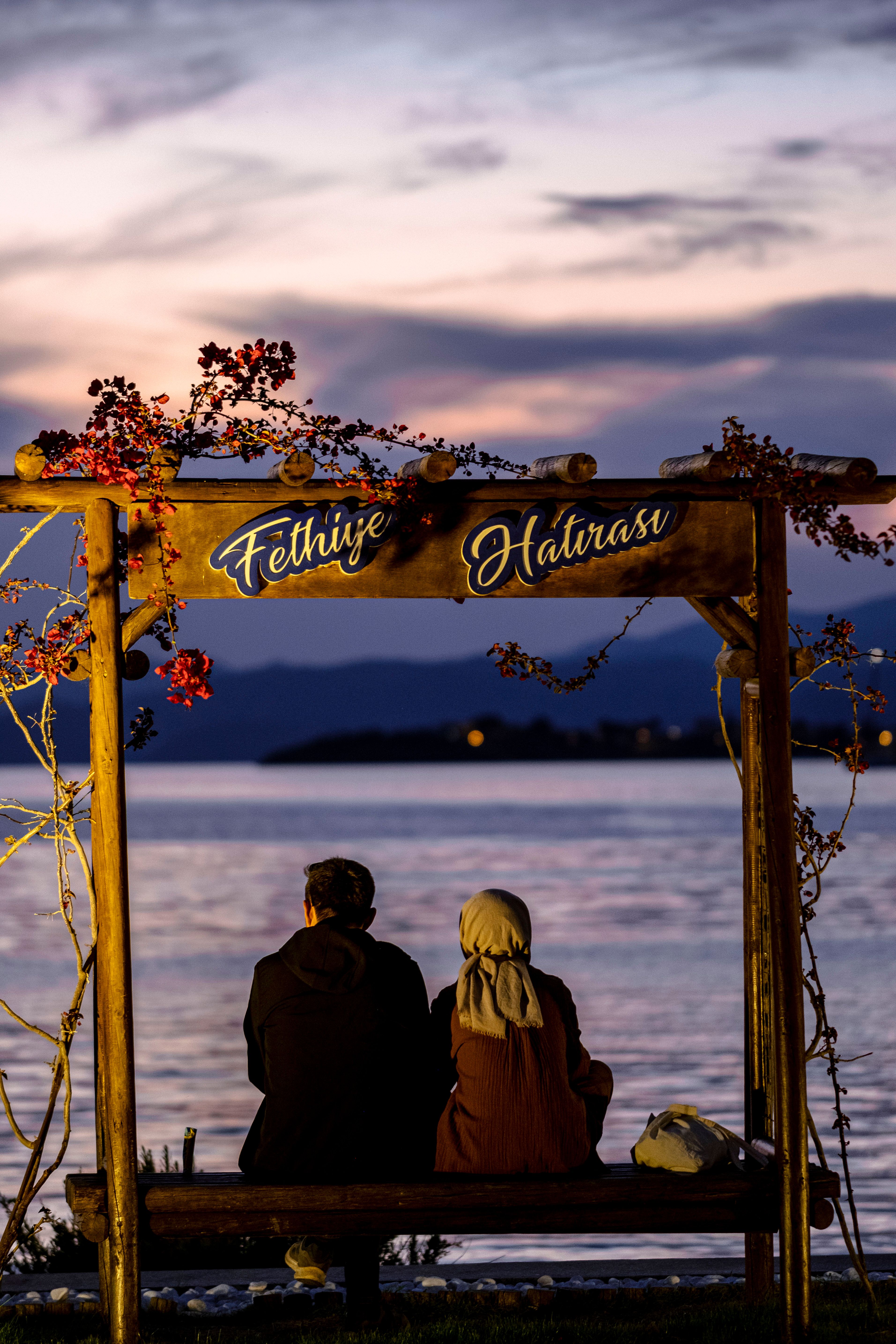 A couple enjoys a peaceful moment by the sea in Fethiye, Turkey at dusk.