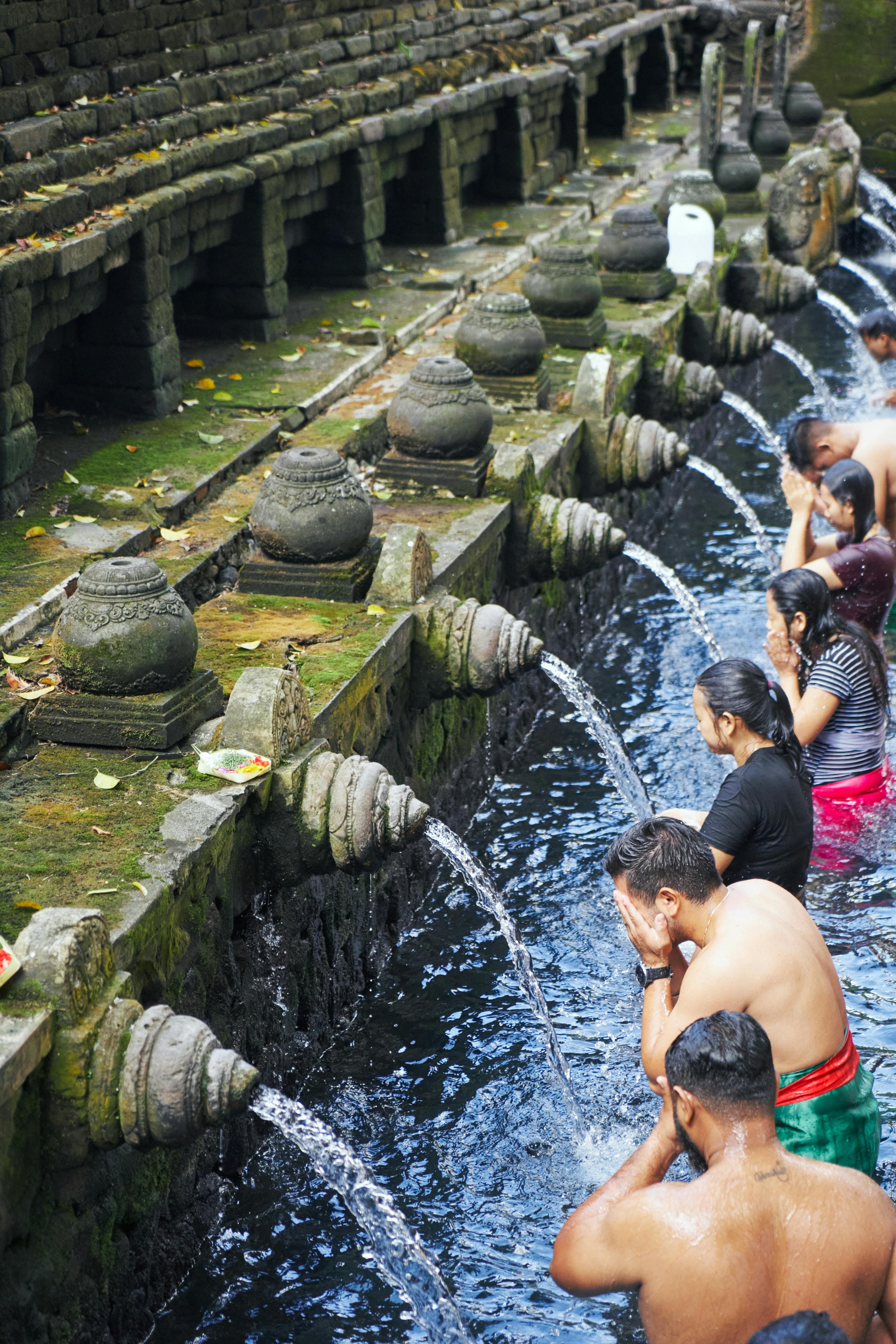 Worshippers in sarongs performing the melukat purification ritual under the holy-water spouts at Tirta Empul Temple near Ubud