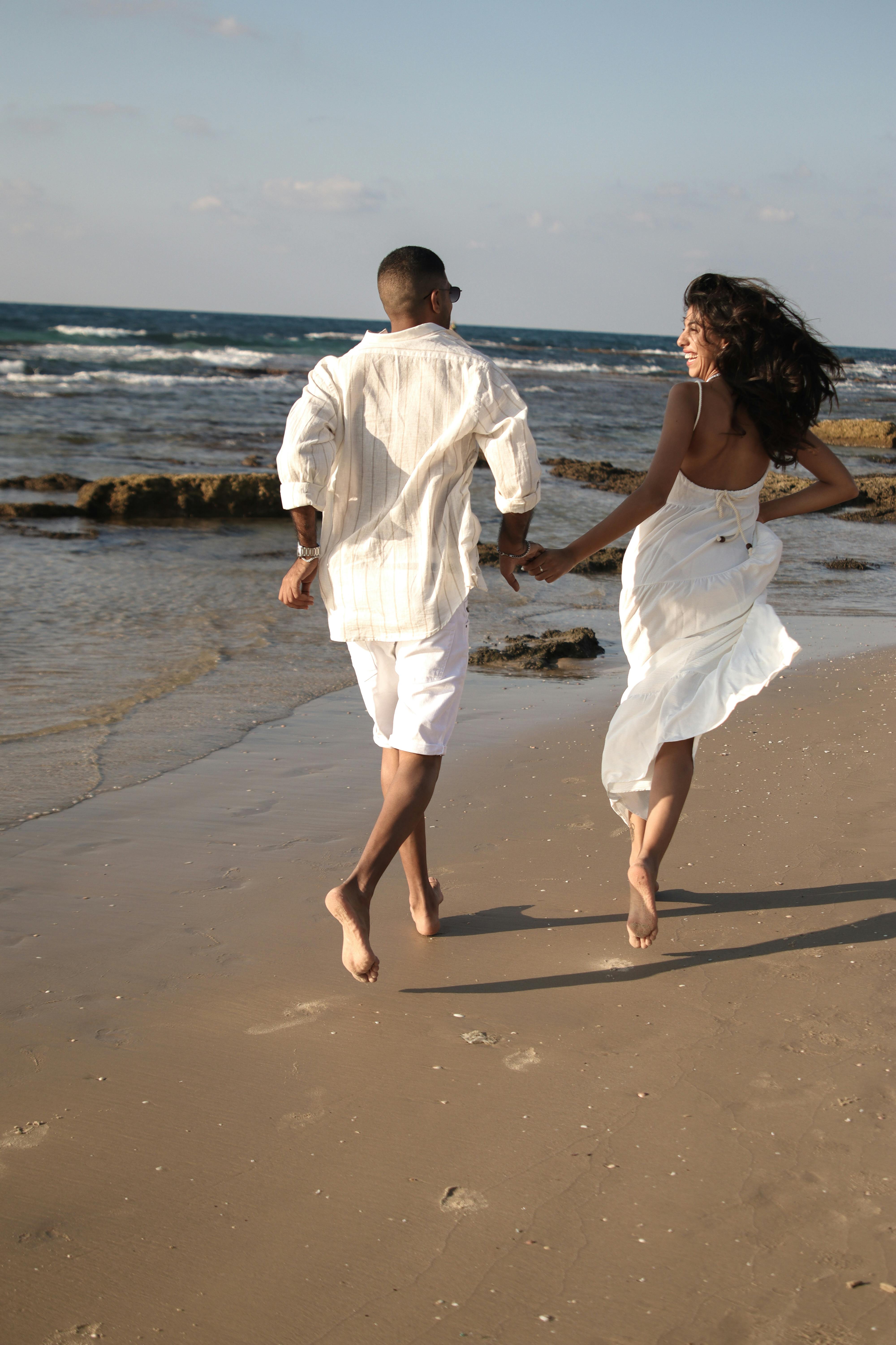 Pareja corriendo juntos por una playa de arena al atardecer