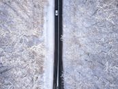 从空中俯瞰，一辆汽车正沿着克罗地亚白雪皑皑的冬季道路行驶