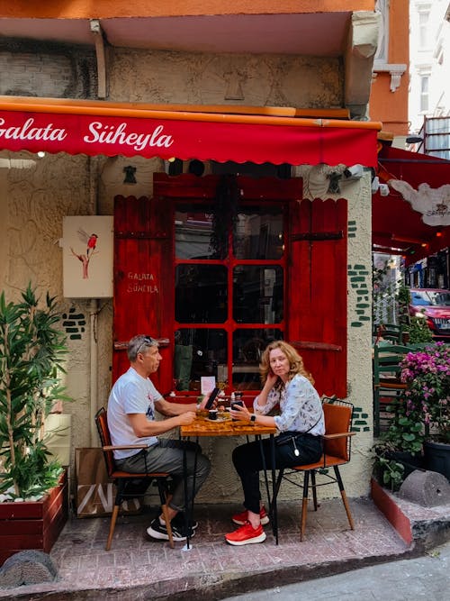 Woman and Man Sitting by Restaurant Table on Sidewalk in Town in Turkey
