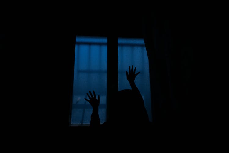 Silhouette Of A Person Touching A Window In A Dark Room