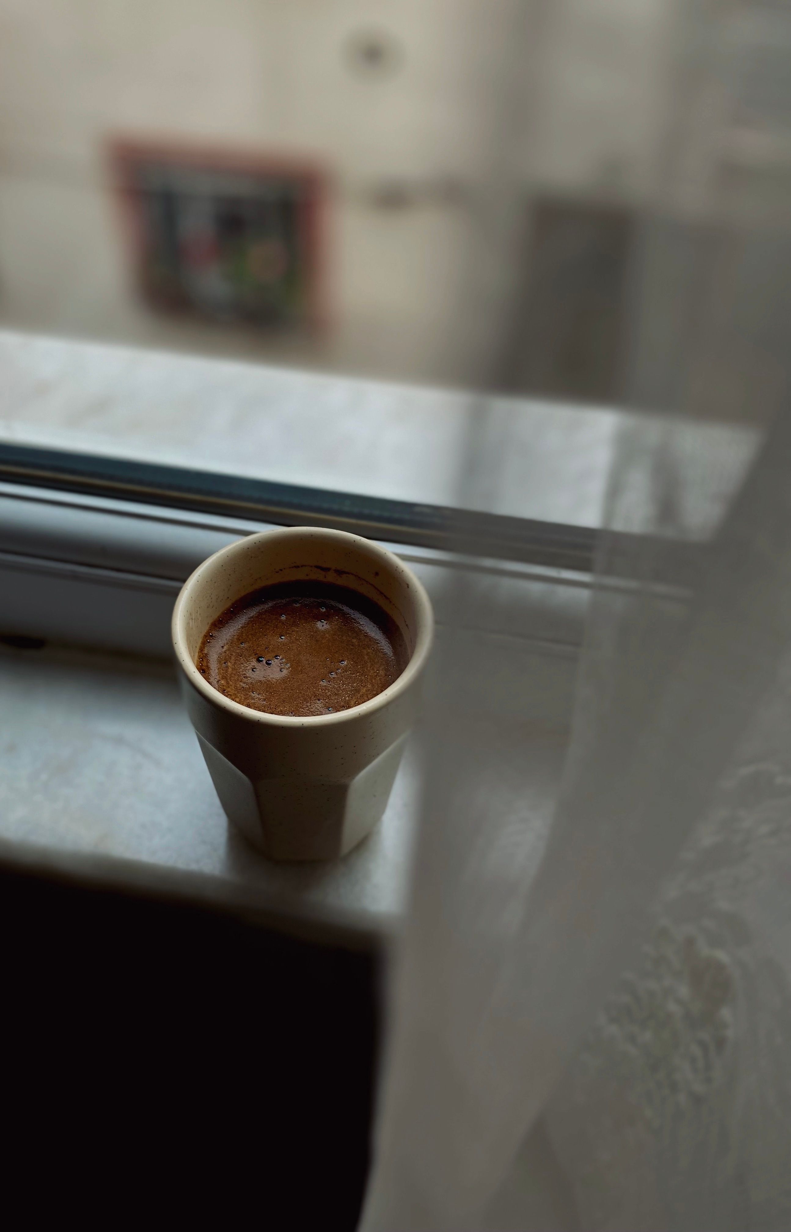 A morning coffee cup next to a small dish of supplement capsules on a windowsill
