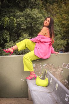 Woman in bright outfit posing on a concrete bench outdoors in CDMX.