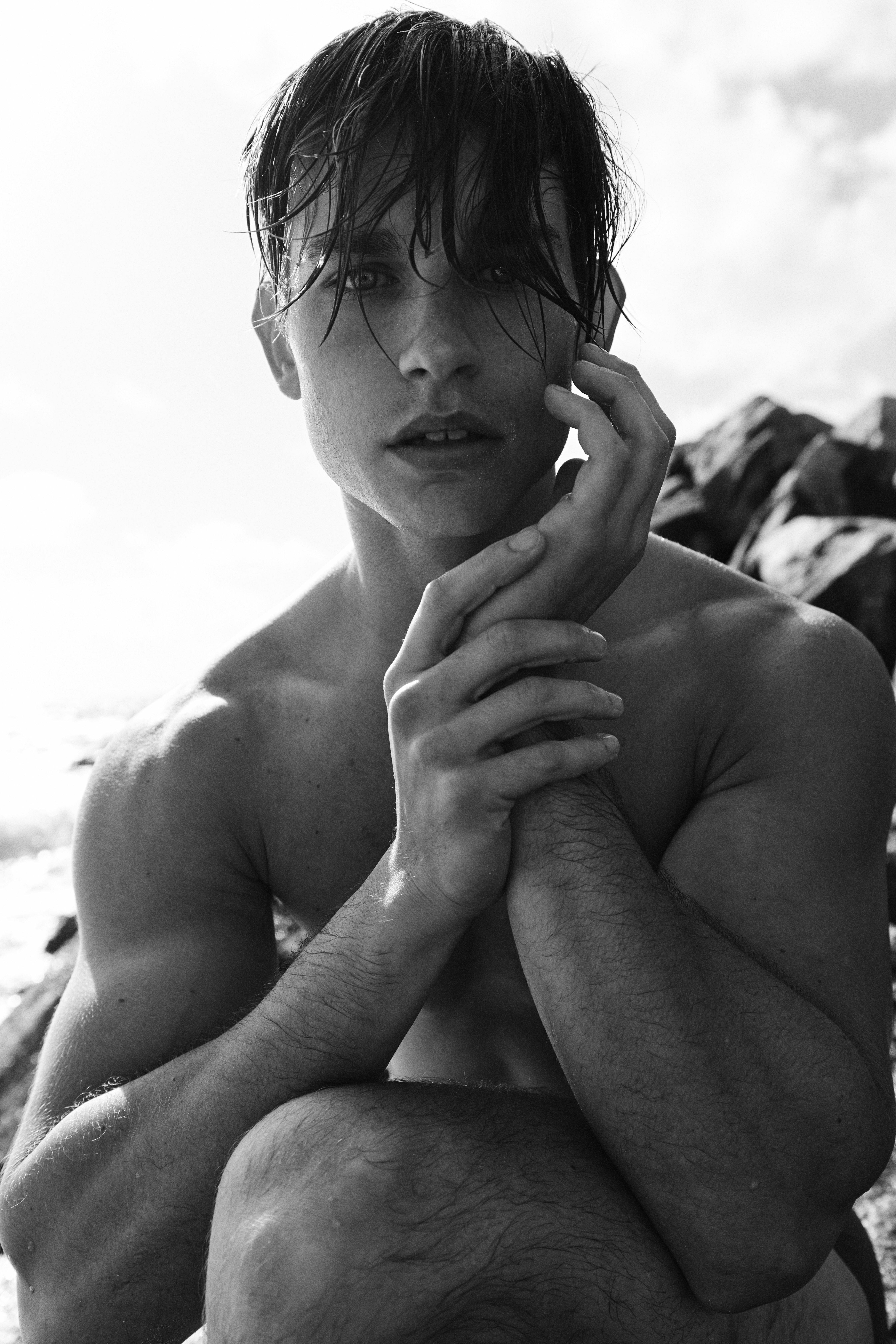 Striking black and white portrait of a young man posing outdoors with a dramatic expression.