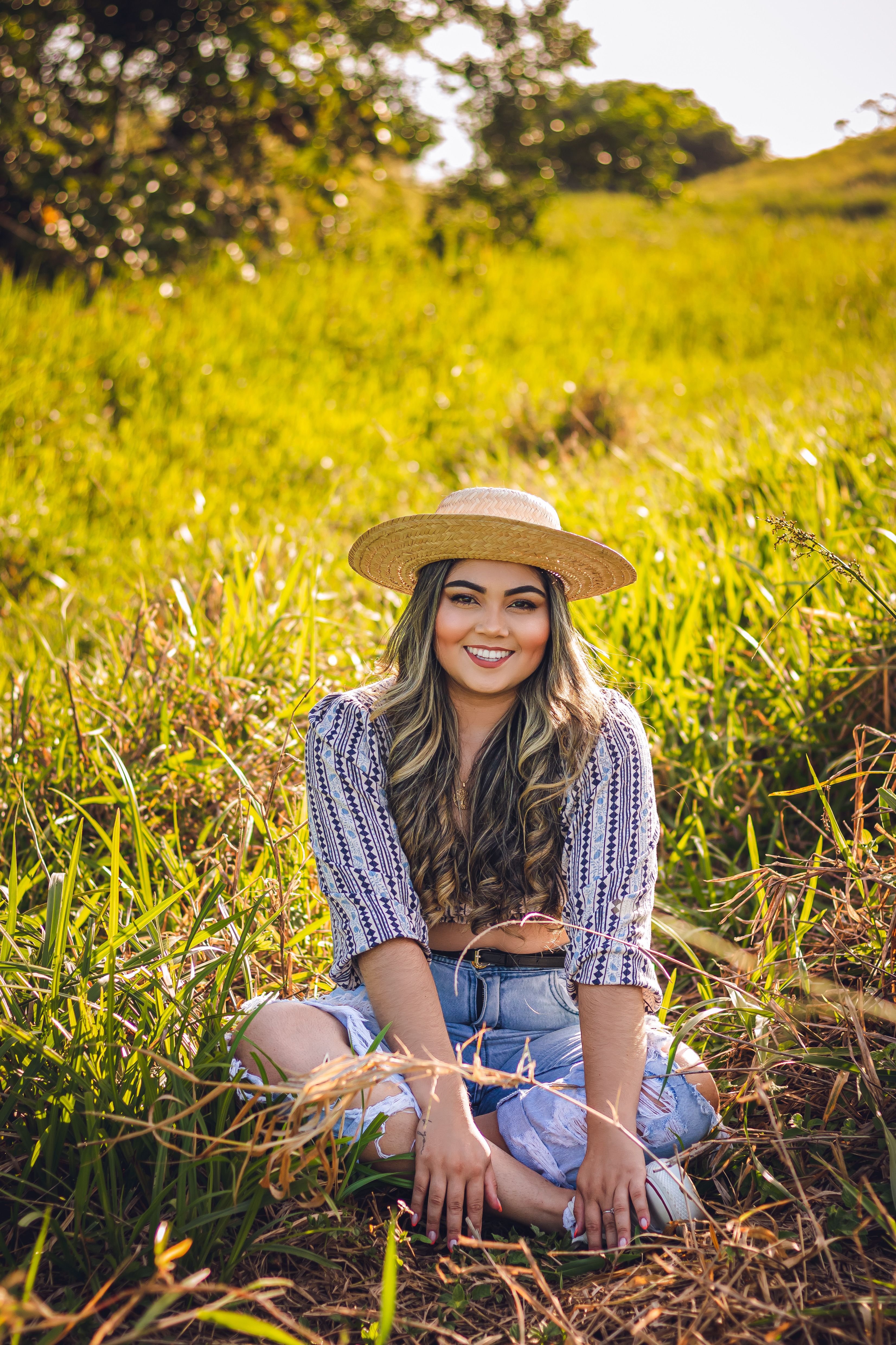 Young Woman Wearing a Hat Sitting on a Grass Field · Free Stock Photo