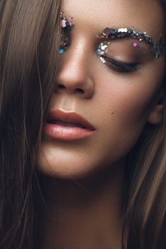 Artistic close-up portrait of a woman with glittering eye makeup and soft expression.