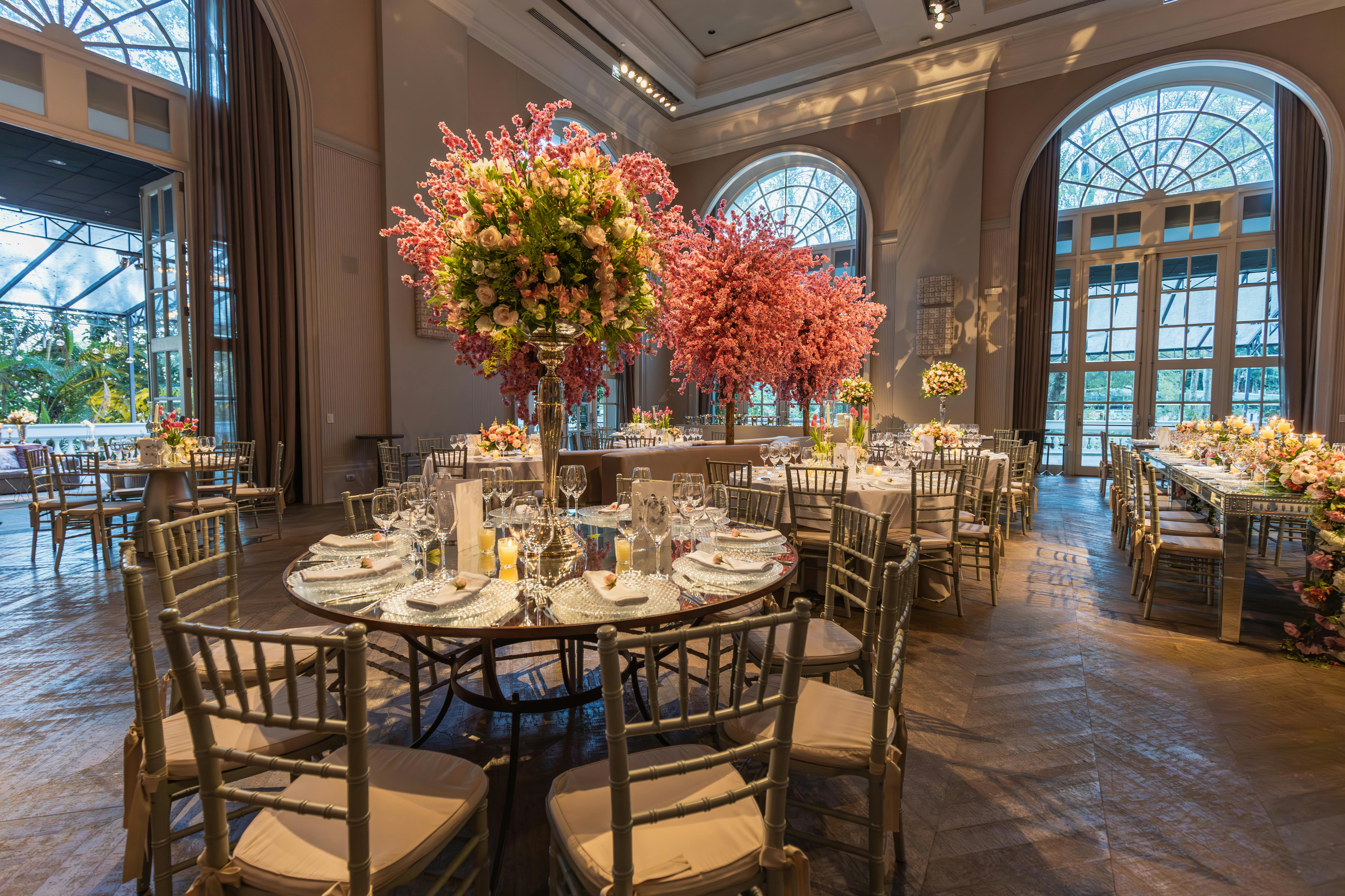Luxurious indoor venue with grand floral centerpieces and set tables, ideal for weddings or celebrations.