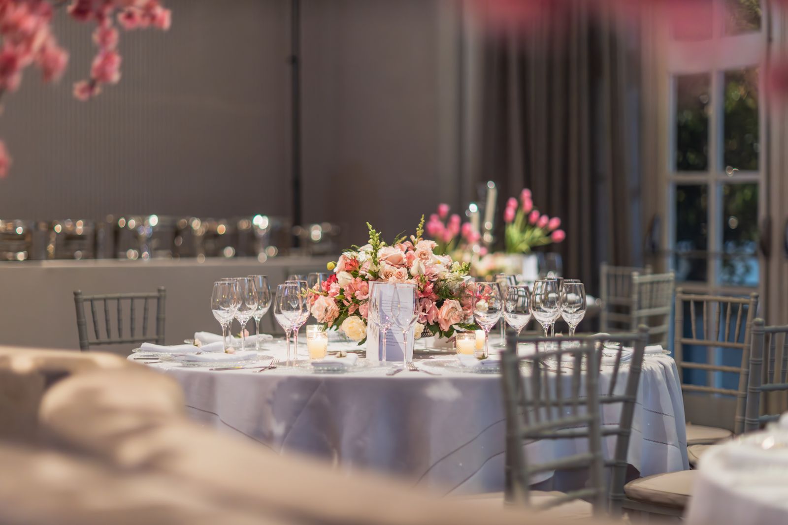 A restrained event table with pink flowers and simple glassware.