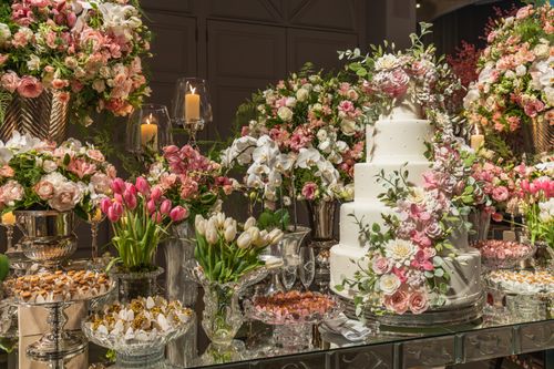 Free A beautifully decorated wedding cake surrounded by elegant floral arrangements and candles. Stock Photo
