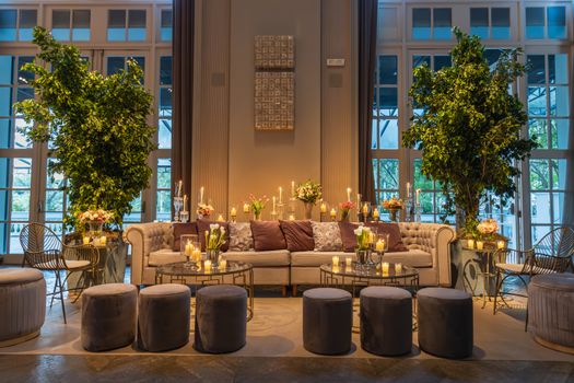 Restaurant Sofa Surrounded by Decorated Coffee Tables, Potted Trees and Ottoman Stools