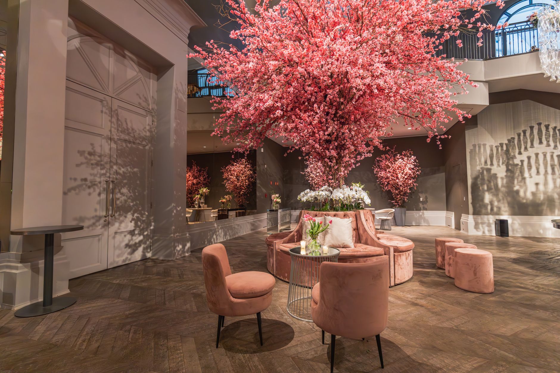 Luxurious hotel lobby adorned with pink cherry blossoms and stylish seating arrangement.
