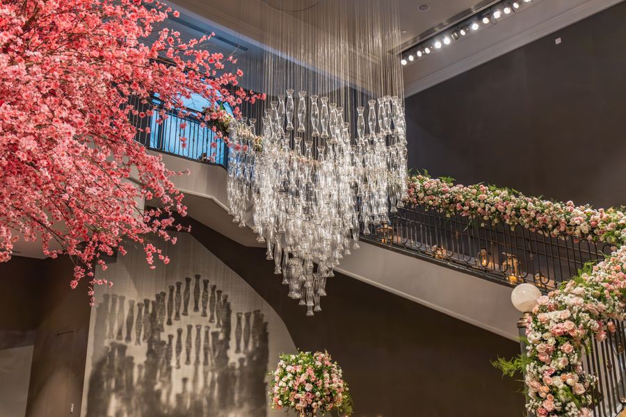 Floral staircase decoration beneath a crystal chandelier