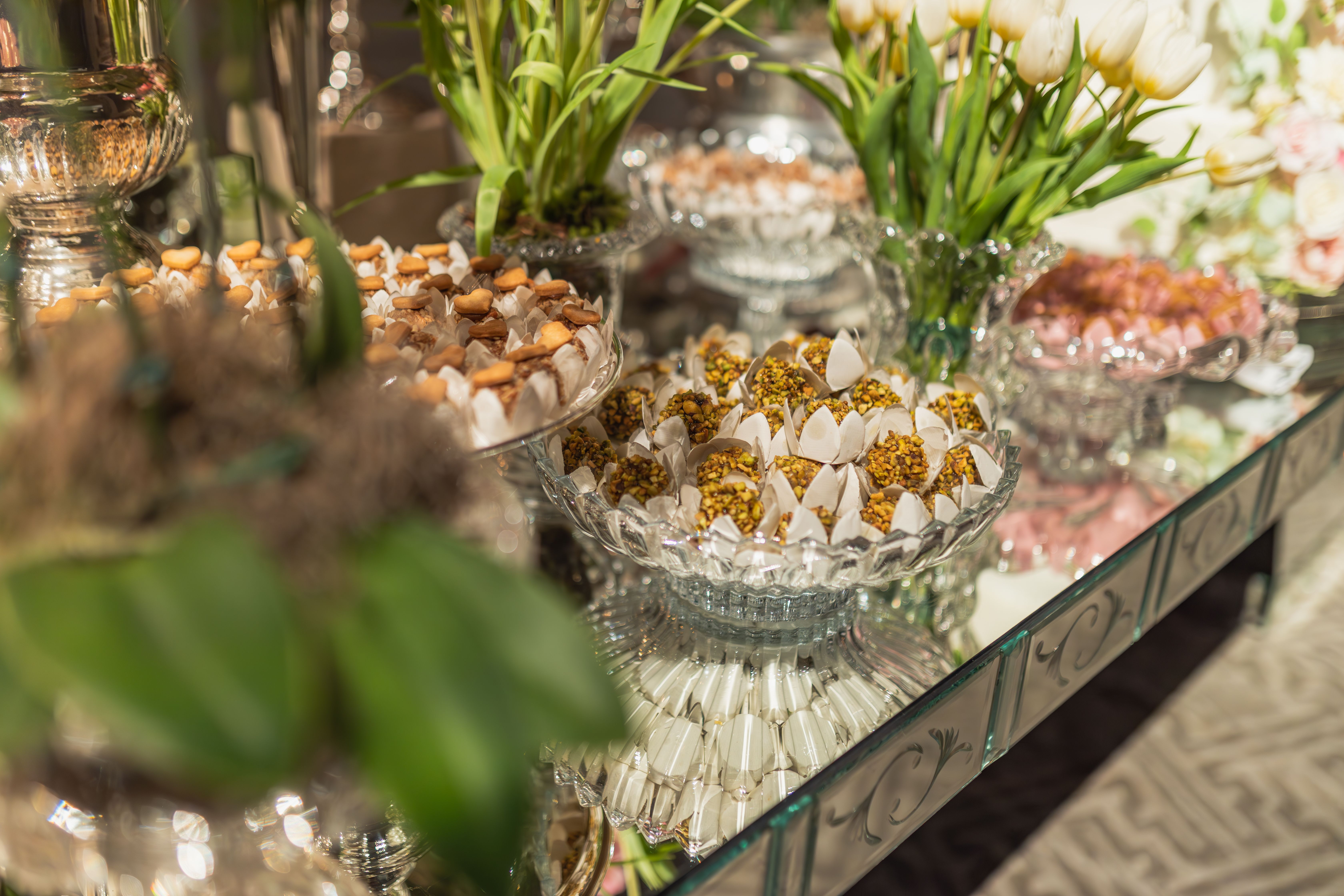 Beautifully arranged sweets and flowers on a mirrored table, perfect for events.