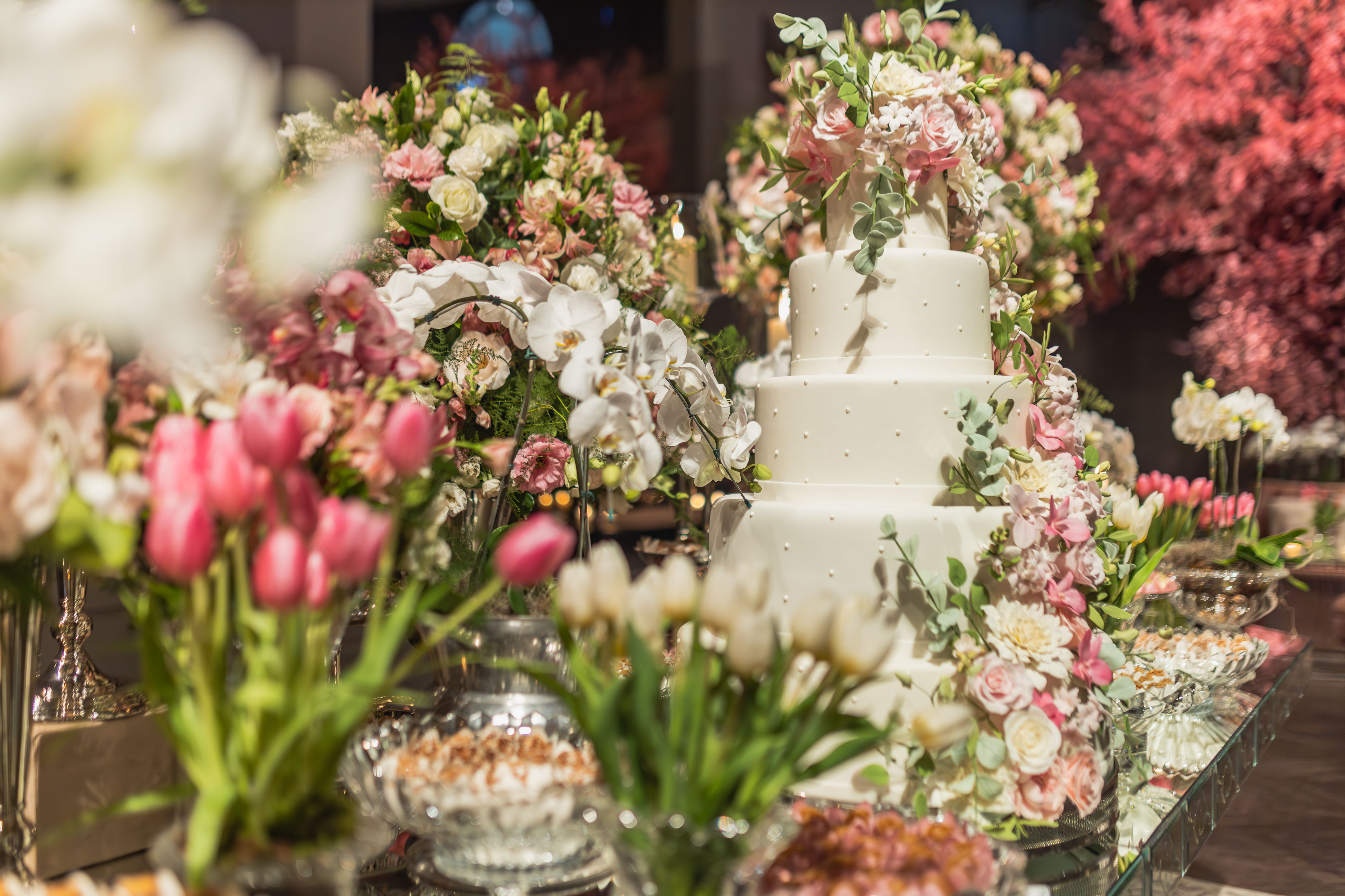 A stunning tiered white wedding cake beautifully decorated with pink and white flowers, perfect for a spring celebration.