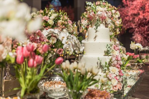 Free A stunning tiered white wedding cake beautifully decorated with pink and white flowers, perfect for a spring celebration. Stock Photo