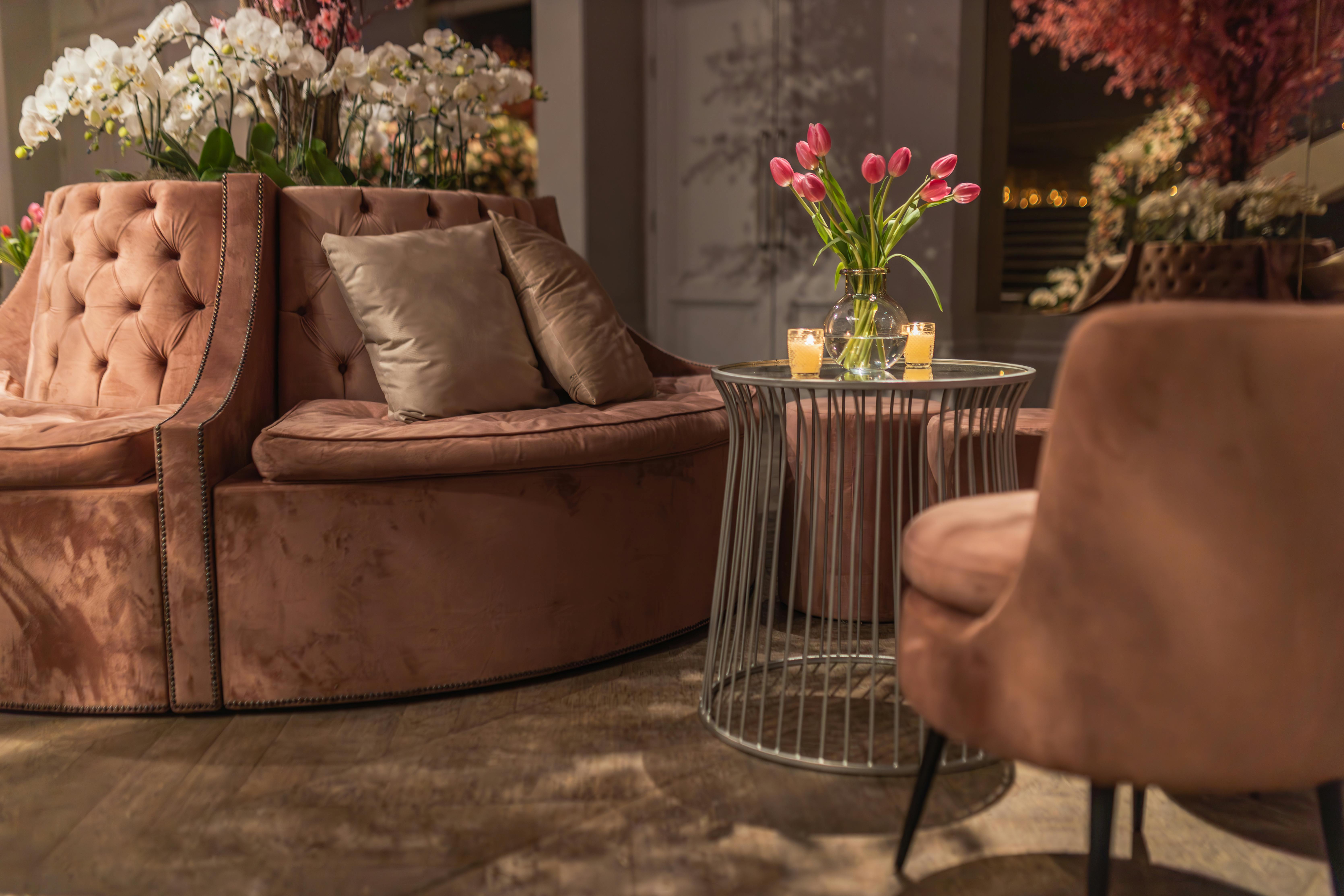 Free Luxurious indoor lounge featuring pink tulips and velvet seating, creating a warm ambiance. Stock Photo
